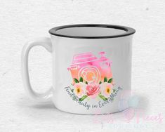 a white and black coffee mug with pink flowers on it's side, in front of a white background