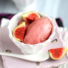 a white bowl filled with ice cream next to sliced figs on top of plates