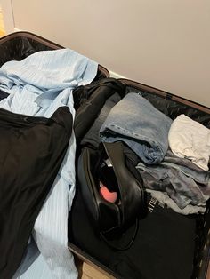 an open suitcase filled with clothes on top of a wooden floor