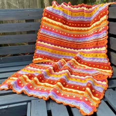 a crocheted blanket sitting on top of a wooden bench