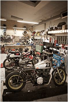 two motorcycles are parked in a garage with many other items on the shelves behind them