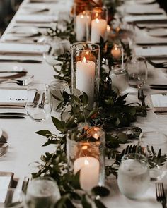 a long table with candles and greenery on it