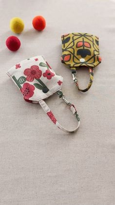 two small purses sitting next to each other on a white tablecloth with pom poms