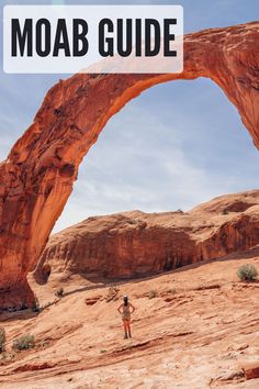 a man standing in front of an arch shaped rock formation with the sky above him