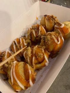 a box filled with pastries covered in icing and cinnamon on a wooden stick