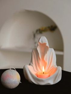 a candle that is sitting on a table next to a white object with a light in it