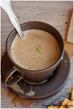 a cup of coffee with a spoon in it on a saucer next to crackers