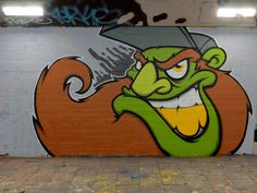 graffiti painted on the side of a building depicting a green monster with a knife in his mouth