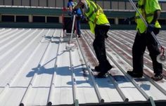 two men in yellow vests are cleaning the roof