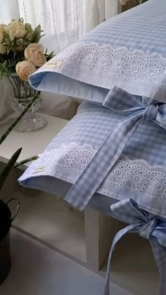 two pillows with bows tied around them sitting on a table next to vases and flowers