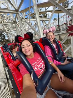 two women in minnie mouse ears sitting on a roller coaster