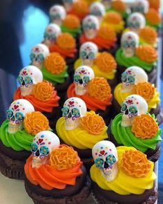 cupcakes decorated with sugar skulls and colorful icing are arranged in a row