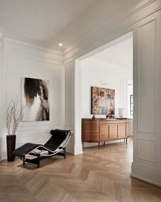 a living room filled with furniture and a painting hanging on the wall over a wooden floor