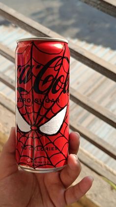 a hand holding a can of soda with spider - man on the front and side