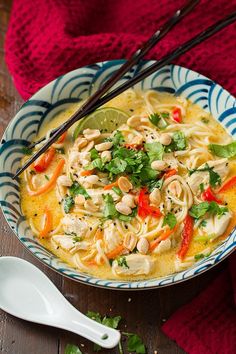 a bowl of chicken noodle soup with chopsticks