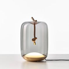 a glass vase with a key hanging from it's side on a white table