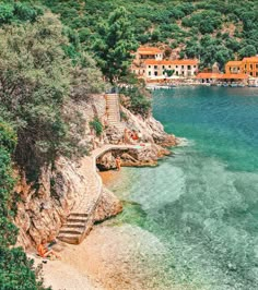 the water is crystal blue and clear with steps leading up to houses on the shore