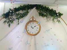 there is a clock hanging on the wall with flowers and butterflies all around it,