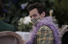 a man with purple hair wearing a plaid coat and matching face mask at an outdoor event