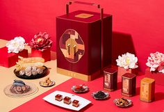 an assortment of desserts and pastries on a red table with pink flowers in the background