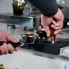 a person is holding a cup and pressing something on the burner with their hands