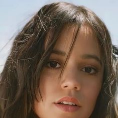 a close up of a woman with long hair and brown eyes looking at the camera