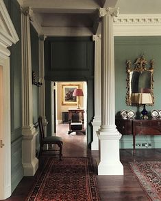 an ornate hallway with columns and rugs on the floor, along with two chairs