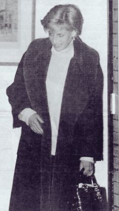 an old black and white photo of a woman carrying a handbag in her right hand