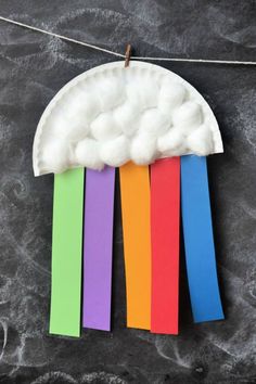 a paper plate with rainbows and clouds hanging from it's side on a string