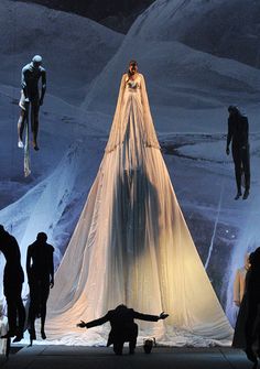 a group of people standing on top of a snow covered ground next to mannequins