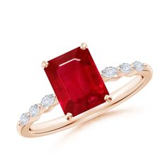 an engagement ring with a large red stone and two white diamonds on the band, set in 18k rose gold