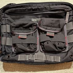 the inside of a black bag with multiple compartments and straps on it sitting on top of a carpeted floor