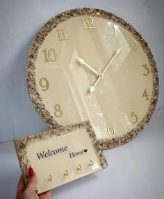 a person holding up a welcome home clock