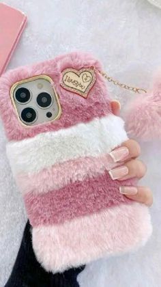 a pink and white fuzzy phone case with pom - poms on the side