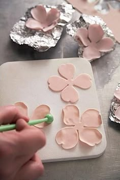 a person is painting flowers on a piece of paper