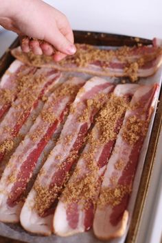 bacon is being cooked on a pan with seasoning sprinkles and spices