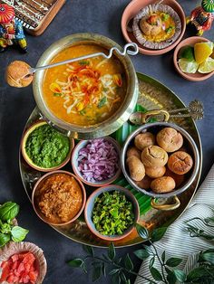 an assortment of food on a platter with bowls and spoons next to it