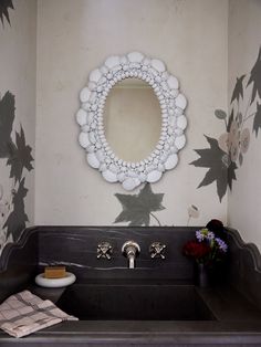 a bathroom sink sitting under a mirror next to a flower wallpapered wall with leaves on it