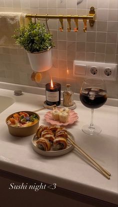 food and wine on a kitchen counter with candlelight in the background at night time