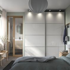 a bedroom with an open closet and clothes hanging on the wall, next to a bed