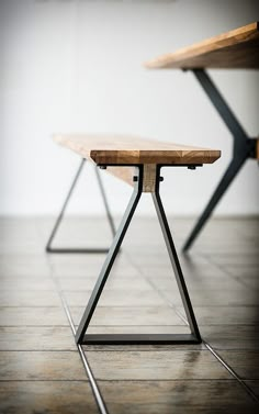 two wooden benches sitting next to each other on top of a tile floor in front of a white wall