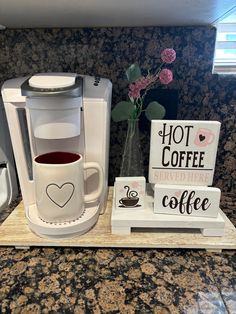 a cup of coffee sitting on top of a counter next to a sign that says hot coffee