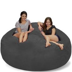 two women sitting on top of a large bean bag chair with their legs crossed and smiling