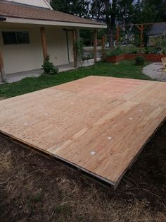 a large wooden floor laying on top of the ground in front of a house and yard