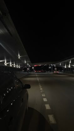 an empty parking lot at night with cars parked on the side and lights shining from above