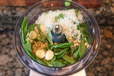 a food processor with spinach, beans and parmesan cheese in it on a granite counter top