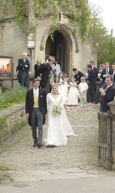 the bride and groom are walking down the stone path in front of their wedding party