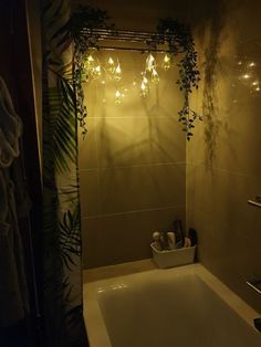 a bath tub sitting under a bathroom mirror next to a shower curtain with lights on it