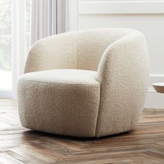 a white chair sitting on top of a hard wood floor next to a table and window