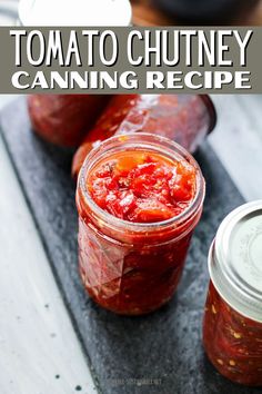 two jars of tomato chutney sitting on top of a cutting board